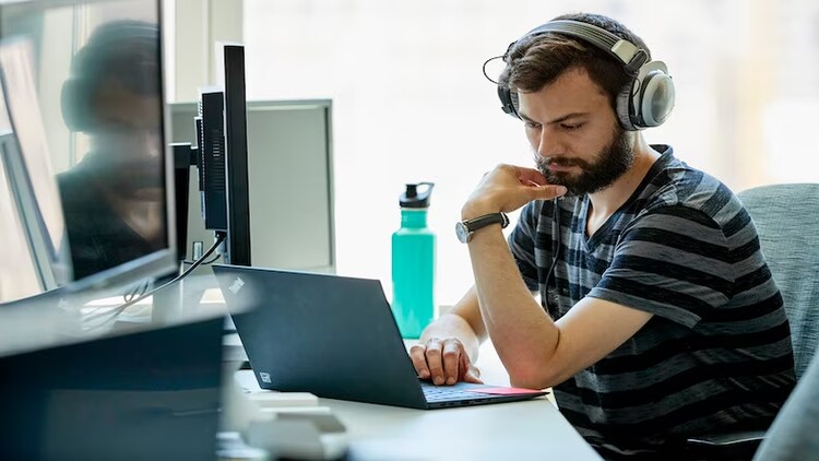 Man listening to head phones while on a computer