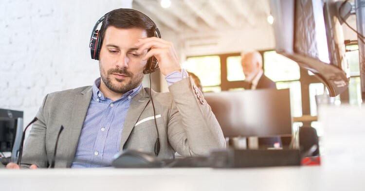 Tired call center operator having a headache in office