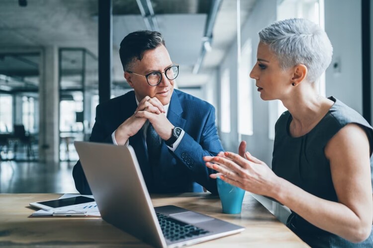 Man and woman sitting at a laptop talking