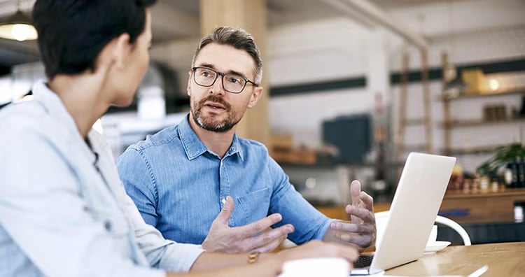 Two men conversing at their computers