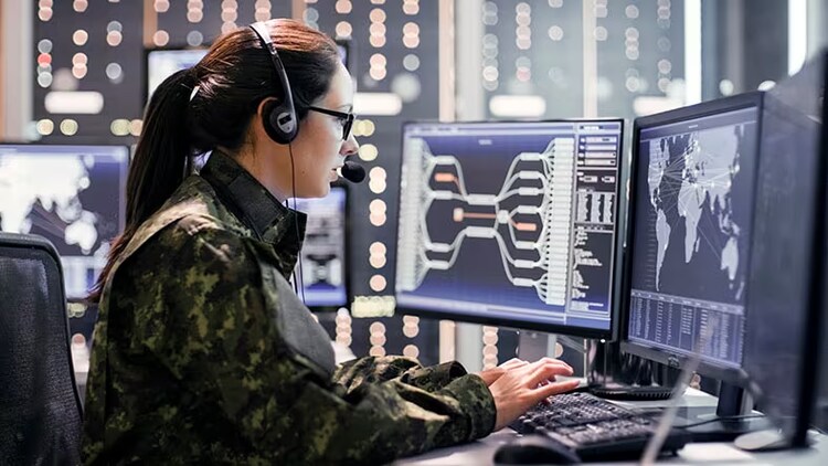 Zero-trust architecture: A military woman types on a keyboard while looking at three monitors.