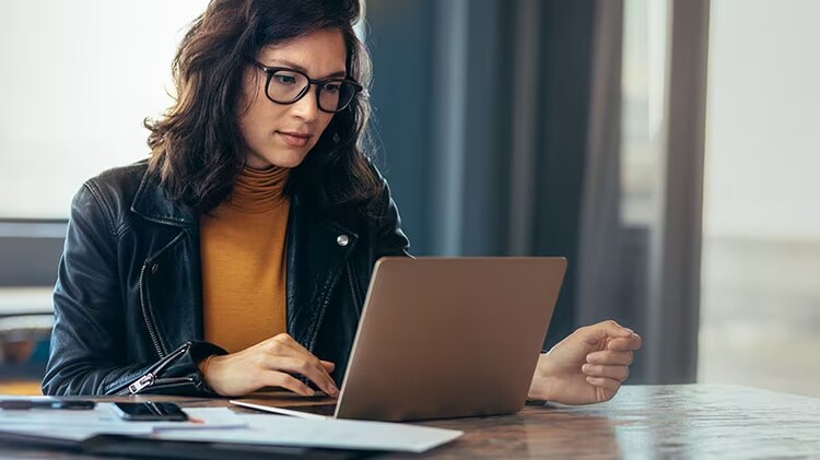 A businesswoman works on a laptop at an office.