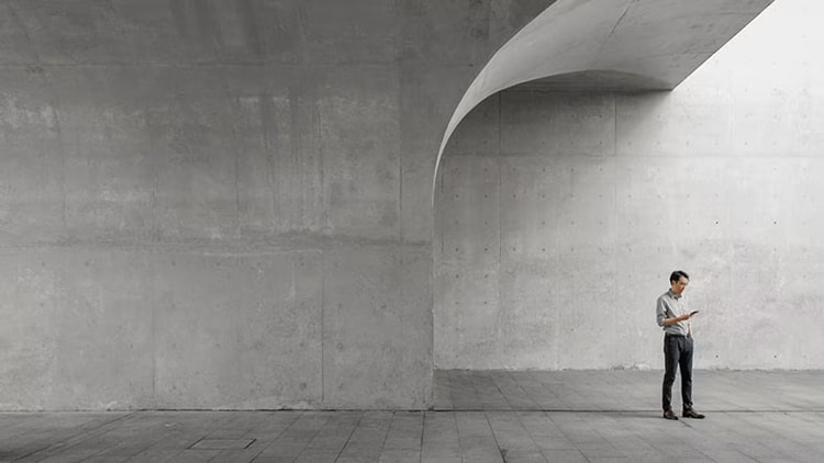 Improving telecommunications: A businessman stands in a concrete structure holding a phone.