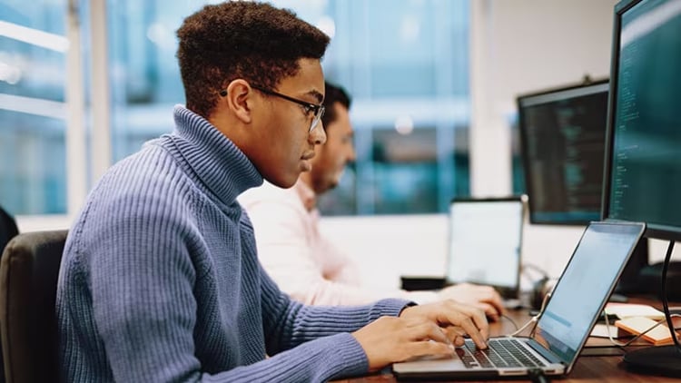 A man with glasses typing on a laptop.