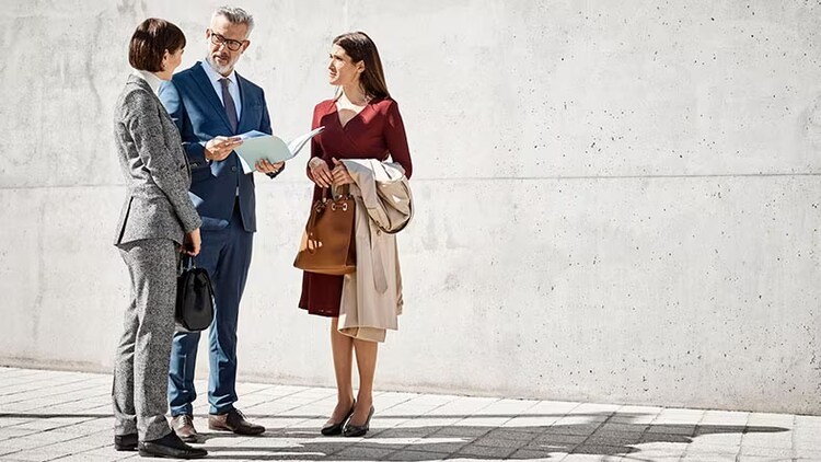 Citizen and employee experience in government: 3 businesspeople stand outdoors in a discussion.