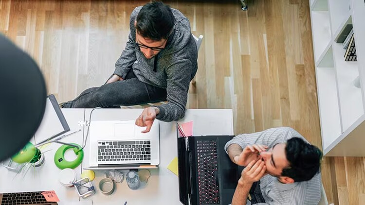 IT asset discovery: Two male workers hover over their laptops.