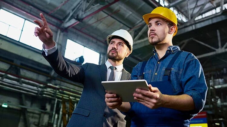 Field service management: 2 co-workers with hard hats standing in a warehouse