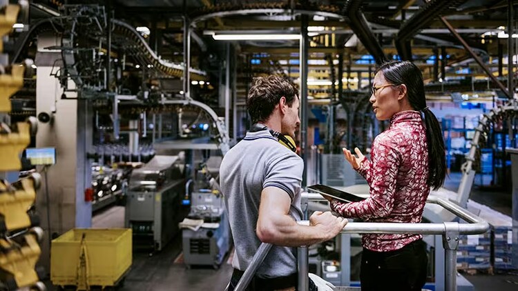 Two manufacturing employees discuss work in a lab.