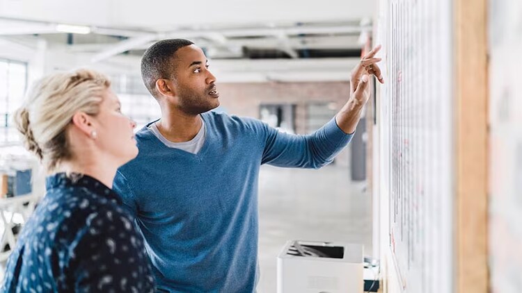 Project portfolio management: 2 employees looking at a whiteboard