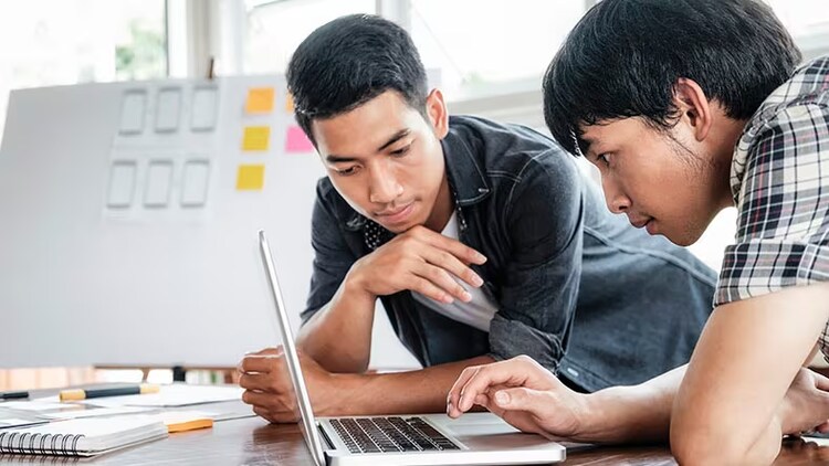 Two teenage boys look at a laptop computer. Maturity matters a lot in operational risk management.