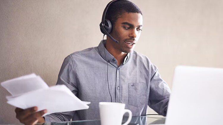 Customer service delivery: A businessman wears a headset while working on his laptop.