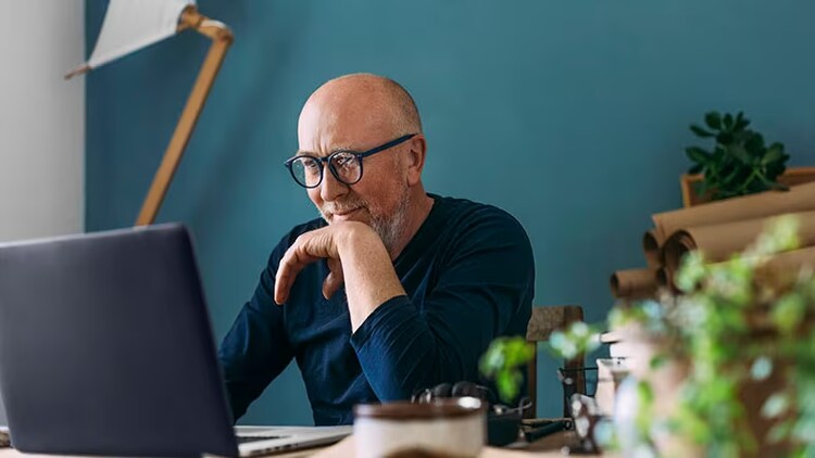Customer engagement: A man sits in front of a laptop with a smile on his face.