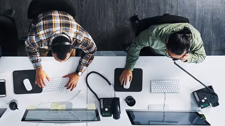 Two IT support workers take calls.