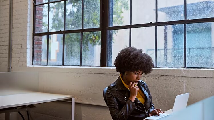 Proactive IT operations: A woman sits at a laptop in an office.