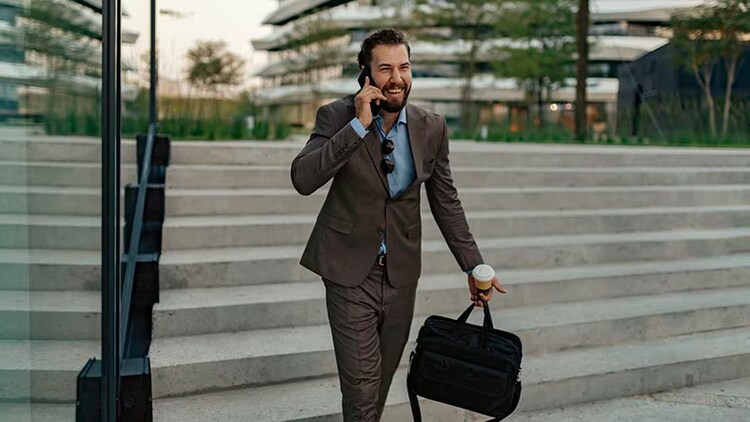 Customer service: smiling businessman on phone walking outdoors