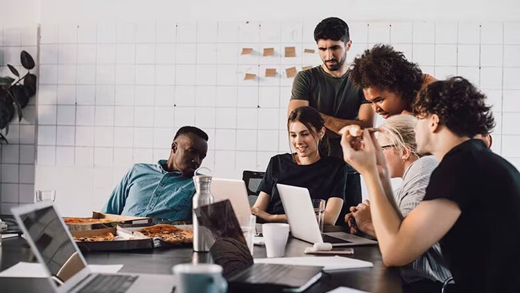 Employee engagement: group of workers in a conference room gathered around a laptop