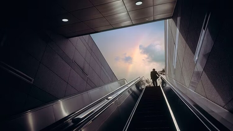 Cloud migration: man on an escalator going up to cloudy sky