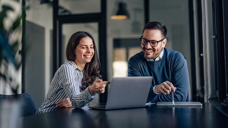 ERP modernization: two co-workers smiling at an open laptop