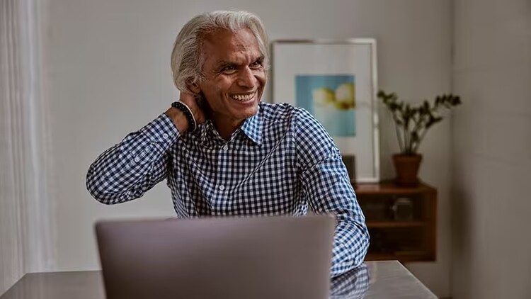 CIOs driving innovation: A seasoned worker sits at a table working on a laptop.