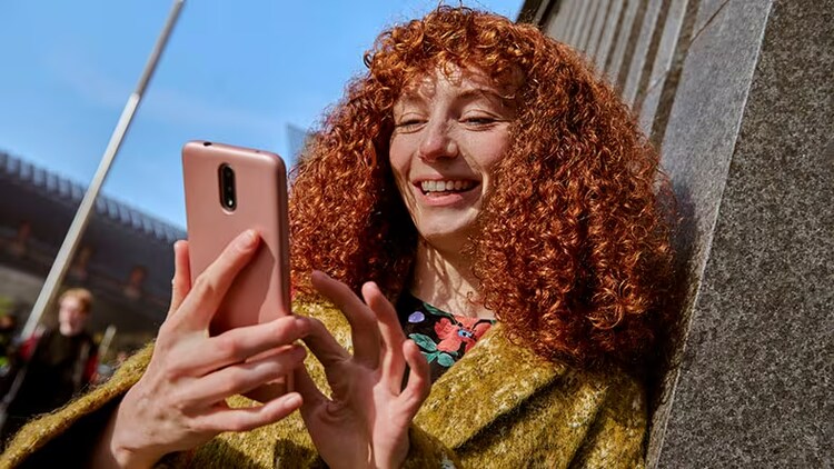 Customer service: woman smiling at smartphone in her hands