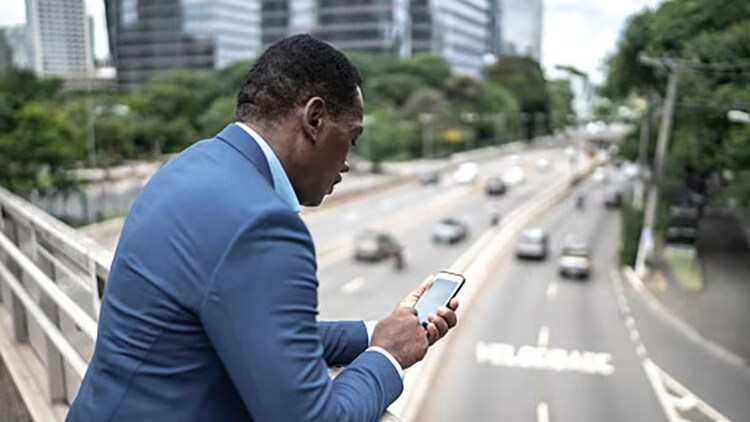 Scaled Agile Framework (SAFe): business man looking at phone while standing on bridge overlooking a city