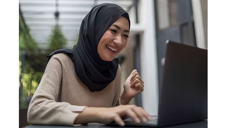 Engaging employee experience: woman in a hijab smiling at a laptop