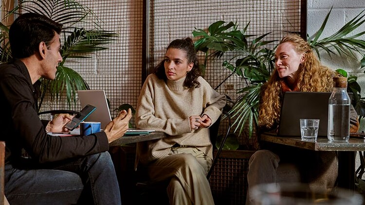 Partner programs: 3 businesspeople with open laptops and a phone discussing work