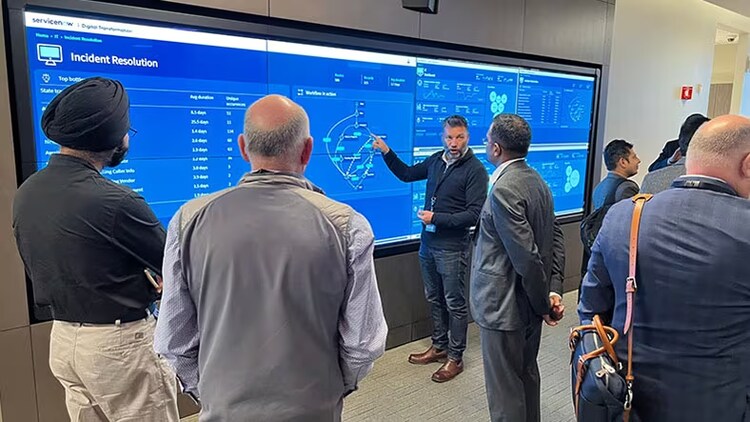 4 businessmen gathered around a life-size display of the CEO Dashboard