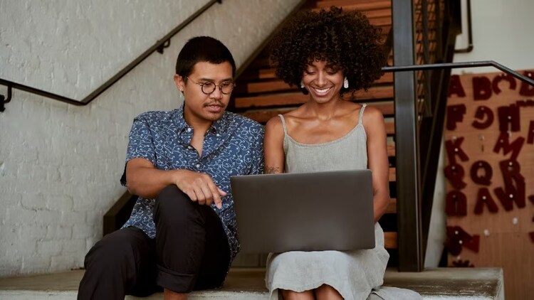 Man and woman looking at computer, smiling