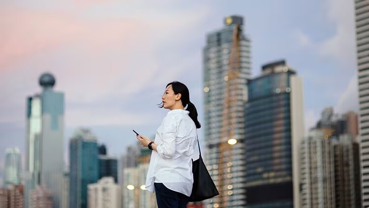 Offboarding: Woman using smartphone outside against cityscape at dusk