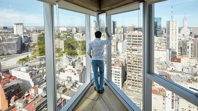 Innovation is a top management imperative: man standing in a corner office overlooking a city