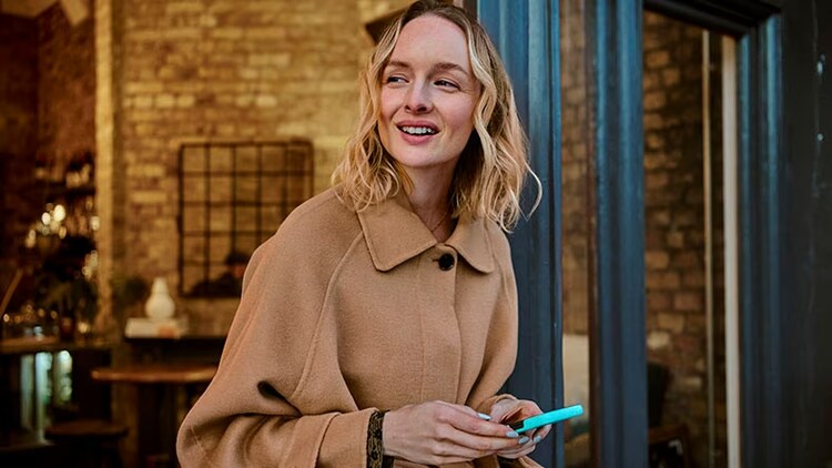 Woman holding phone smiling and looking away