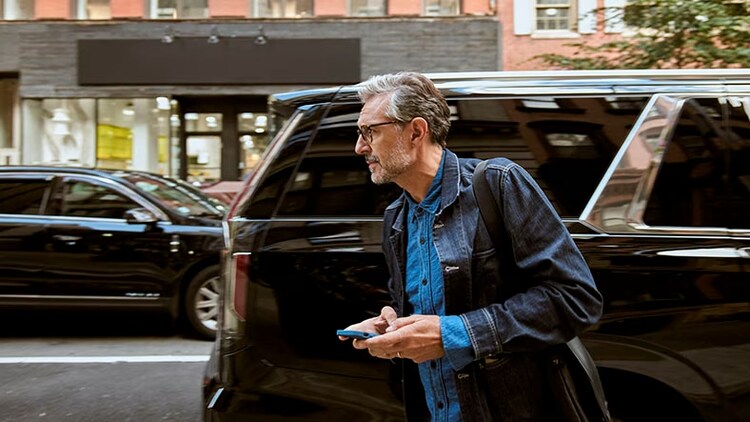 Car parking customer experience: A man walks away from a parked SUV with his cellphone in hand.