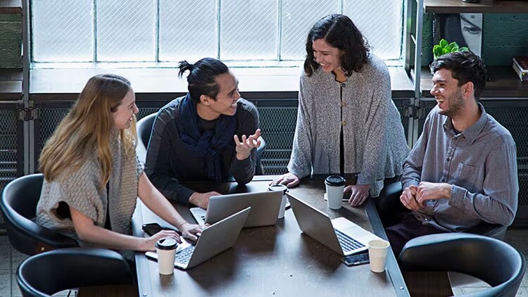 Project management: 4 workers collaborating around a conference table