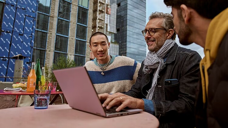Australia customer service generation gap: 2 generations of workers look at a laptop at a table outdoors