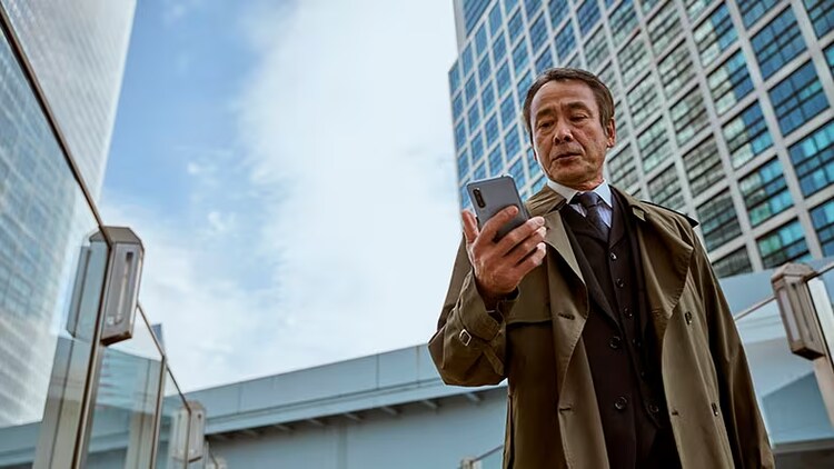 Power of the cloud: A businessman looks at his smartphone under a cloudy sky.