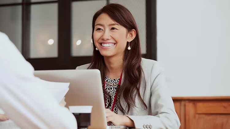 Cyber resilience: woman in front of open laptop smiling at person sitting across the desk from her