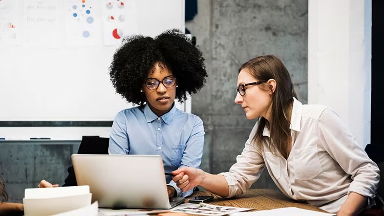 ERP workflows: 2 co-workers looking at and pointing to a laptop