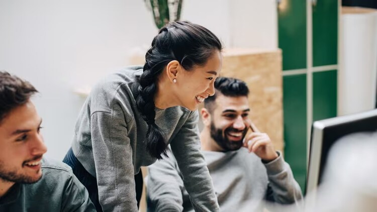 Maximize efficiency: 3 workers smiling at a computer monitor