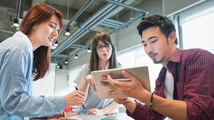 Tech jobs: three early-in-career workers looking at a tablet