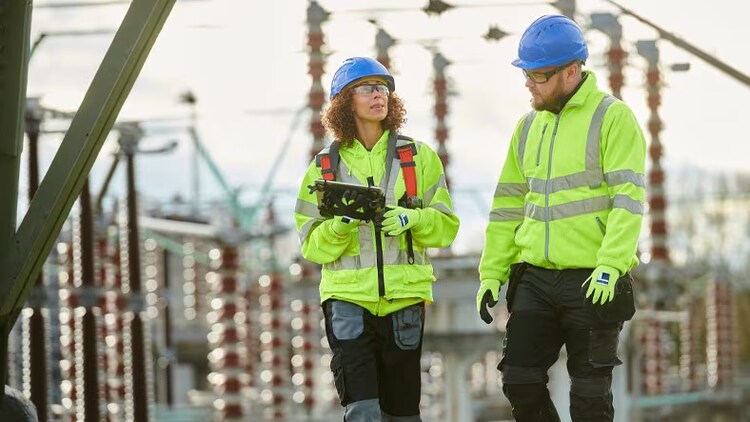 Health and safety: 2 workers in hard hats examining a facility