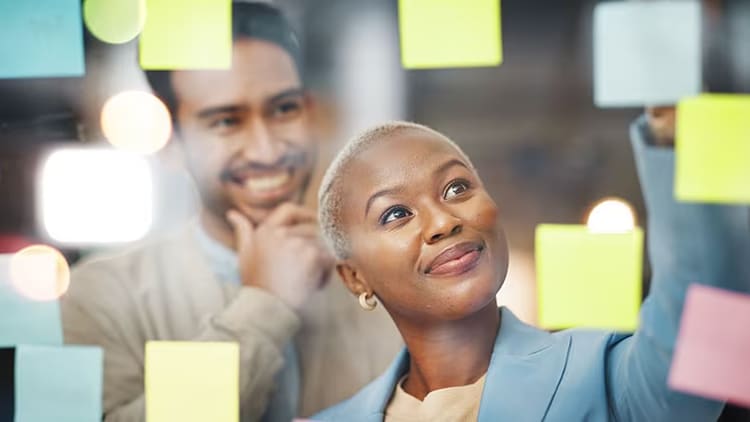Innovation trends: man and woman writing on sticky notes on glass window