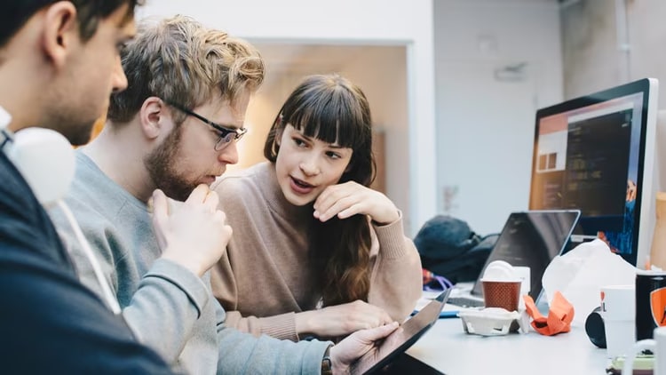 IT asset management strategy: 3 workers in front of a desk looking at a tablet