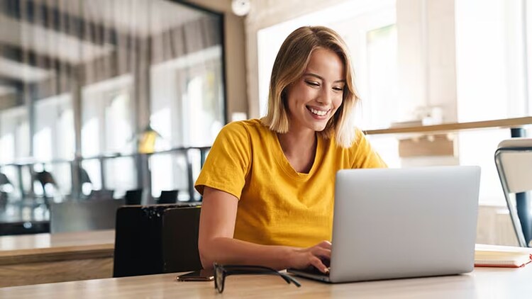 Great customer service meets AI: woman smiling while working on a laptop