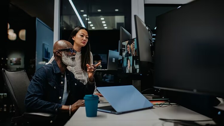 ITSM and ITOM functions: two workers looking at a computer monitor in an office