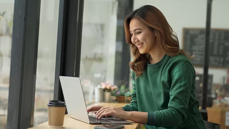 Great experiences: smiling woman working on a laptop