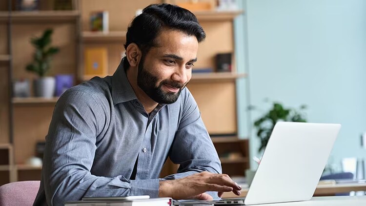 Robotic process automation: man smiling at laptop in a home office