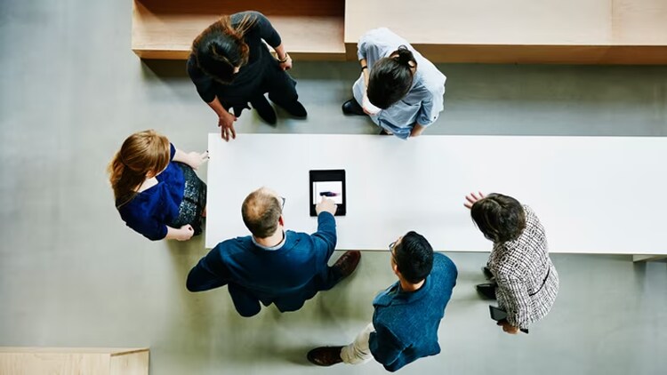 Culture of observability: overhead shot of six workers looking at a tablet on a conference table