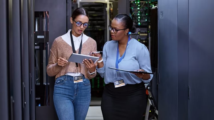 2 system administrators looking at a tablet in a server room