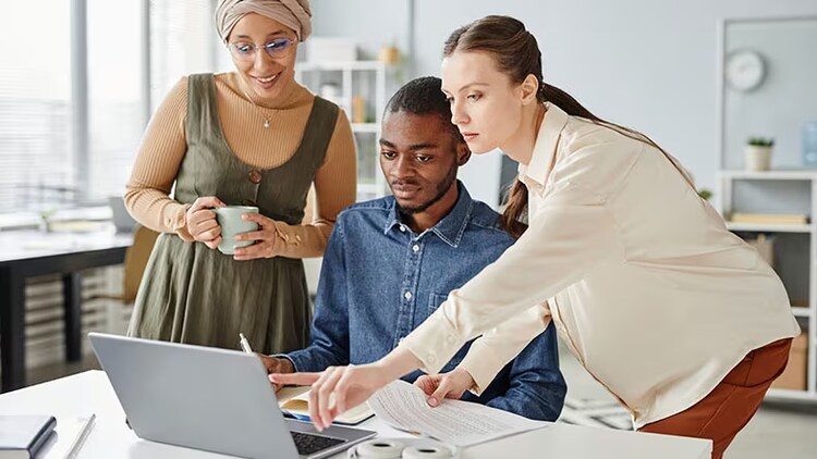 Example of generative AI: three workers looking at a laptop screen